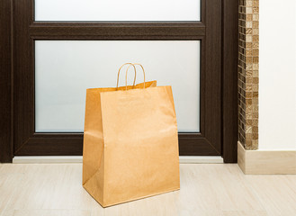 Paper bag near door of house. Safe delivery concept. Contactless home food delivery. Precautionary...