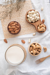 Mix of nuts in wooden bowl. Varieties of nuts with fork and spoon wood and flower on fabric. Top view of Almond, cashew nut, pistachio.