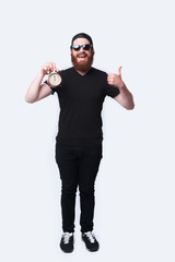 Full length photo man with beard wearing sunglasses and holding alarm clock