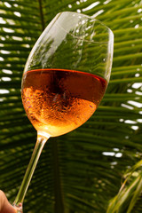 Crystal glass with rose wine in a toast attitude. High class concept. Refreshing alcoholic drink made with grapes.