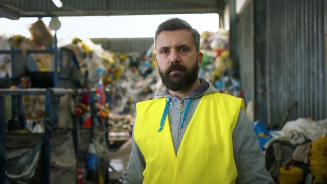 Front view of worker standing on landfill, waste management concept.