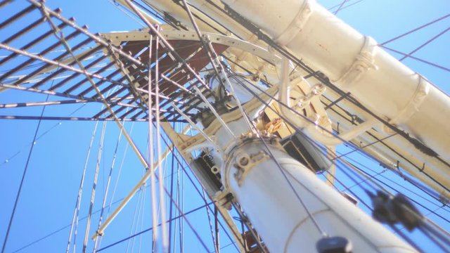 A ships mast with a rolled up sail and ropes. Old traditional sailing ship from the 19th century Rickmer Rickmers with a blue sky. Camera panning movement. Shot in 4K.