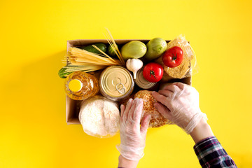 Donation. Hands in medical gloves hold Food supplies crisis food stock for quarantine isolation...