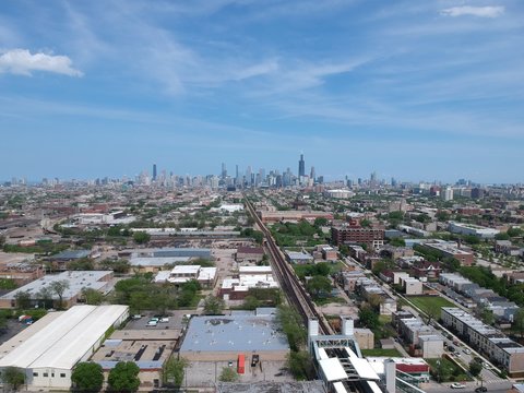 aerial drone footage of an urban community near downtown Chicago over by the CTA Train stop. a complete view of the Chicago skyline during a clear sunny day in  