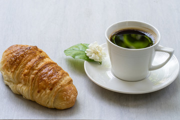 Cup coffee with croissant  on white table.