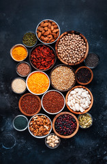 Fototapeta na wymiar Superfoods, legumes, nuts, seeds and cereals selection in bowls on grey background. Superfood as chia, spirulina, beans, goji berries, quinoa, turmeric, mung bean, buckwheat, lentils, flax seed