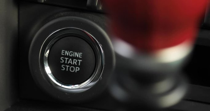 Man is pressing the button engine start stop in car, finger closeup. The driver is driving a car. Preparing to start or stop auto inside it.