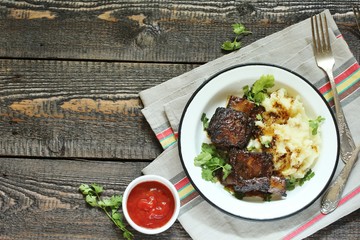 baked short ribs with mashed potatoes.
long stewed meat. rustic style, wooden table, top view, copy space