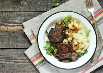 baked short ribs with mashed potatoes.
long stewed meat. rustic style, wooden table, top view, copy space