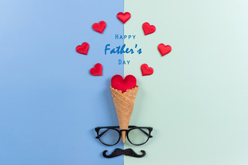 Happy Fathers Day background concept.Decorated ice cream cone, red heart, mustache, eyeglasses on bright pastel background with copy space. Top view, flat lay.