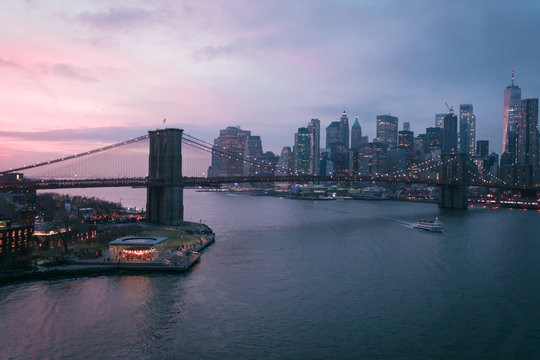 New York City, USA - 26 Dec 2019: Dramatic, colorful Sunset at the East River with Manhattan Skyline Lights and Brooklyn Bridge © christianthiel.net