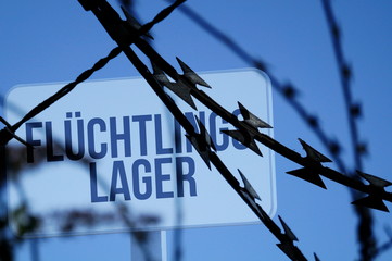 Stacheldraht und Tafel mit dem Hinweis auf ein Flüchtlingslager