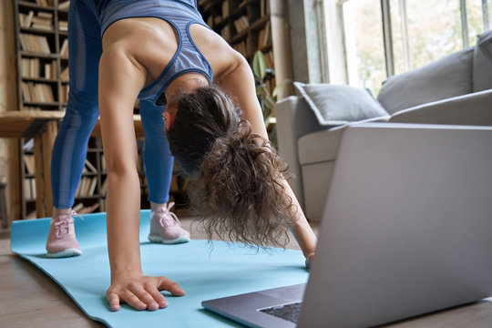 Fit Sporty Hispanic Girl Doing Online Yoga Exercise Stretch On Mat At Home. Active Young Healthy Latin Woman Enjoy Sport Pilates Physical Fitness Training On Laptop Computer Watching Video Class Guide