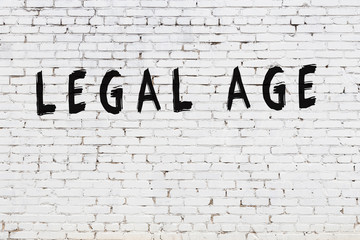 Word legal age painted on white brick wall