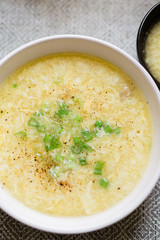 A Close-Up of a Bowl of Egg Drop Soup Served in a White Bowl and Topped with Scallions