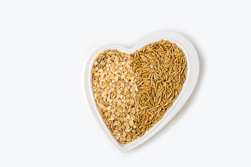 Oatmeal flakes and oats on a heart shaped plate on white background. Healthy breakfast. Organic and vegetarian food. Porridge and cereal concept. Flat lay, copy space for text