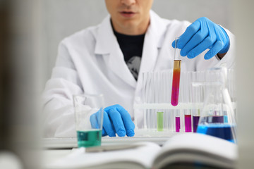 Fototapeta premium A male chemist holds test tube of glass in his hand overflows a liquid solution