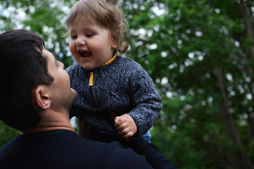 Obraz premium A cute little blonde haired, blue eyed boy plays with his Dad in an outdoor field, fathers day