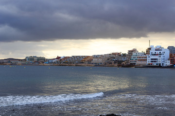 Obraz premium El Medano panorama with hotels, Atlantic Ocean and dark clouds on Canary Island Tenerife, Spain