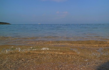 Soft focus of the waves beat at the beach with shell fragments with sunlight and blue sky in summer time. Nature background concept.