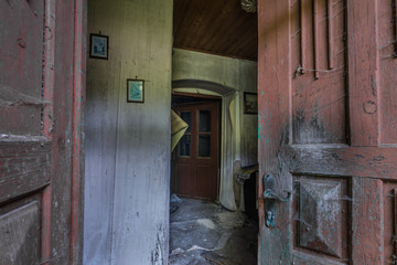 Fototapeta na wymiar open wooden door with a view of an abandoned farmhouse