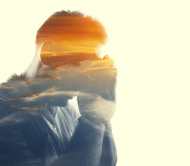 Double exposure of man in the clouds at sunrise or sunset time