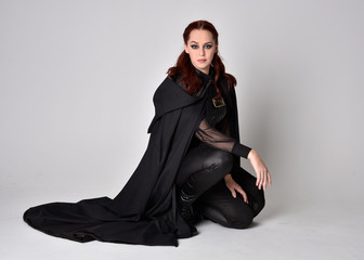 Fantasy portrait of a woman with red hair wearing dark leather assassin costume with long black...