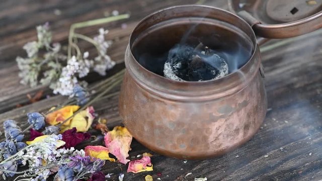 Getrocknete Kr&auml;uter verbrennen auf R&auml;ucherkohle in einer R&auml;ucherschale-R&auml;ucherritual zur Mittsommerwende