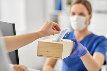 medicine, pandemic and healthcare concept - close up of female doctor or nurse offering mask to patient at hospital