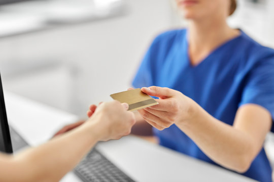 Medicine, People And Healthcare Concept - Close Up Of Patient Giving Female Doctor Or Nurse Insurance Or Credit Card Card At Hospital