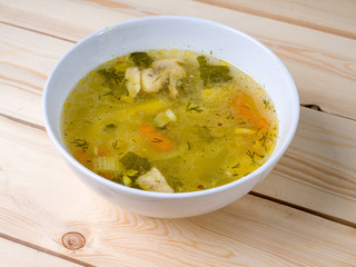 Chicken soup in a bowl on a wooden surface. Hot dish