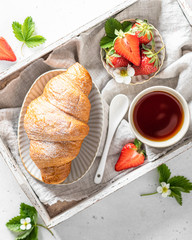 Croissant, tea and strawberries. Breakfast and morning concept, view from above