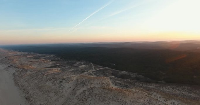 A drone shot moving towards a forest near an empty beach in le Porge