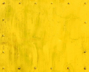 yellow painted metal surface with screw fasteners