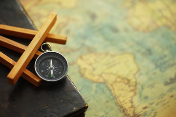 Travel and adventure search concept. Vintage aged map with a shabby book and compass. Shabby book and compass on the table.