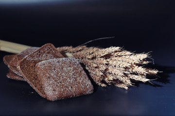 Fresh loaves of bread with wheat and gluten on a black table. Bakery and grocery concept. Fresh, healthy sorts of rye and white loaves food closeup. Fresh homemade bread with cereals.