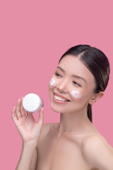Obraz na płótnie Canvas Pretty asian girl holding a jar of face cream