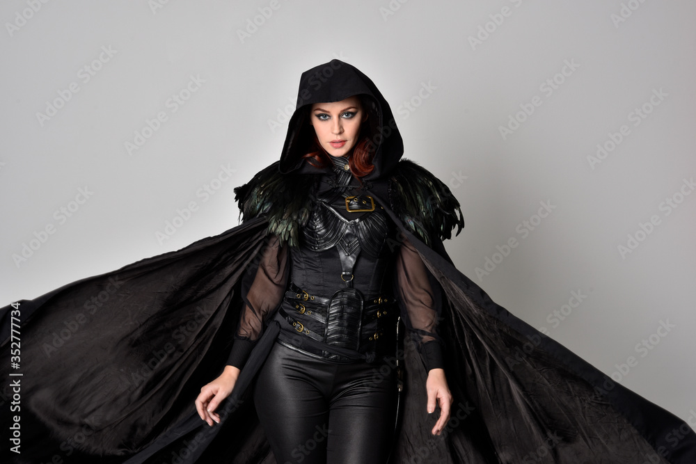 Sticker Close up fantasy portrait of a woman with red hair wearing dark leather assassin costume with long black cloak.  isolated against a studio background.