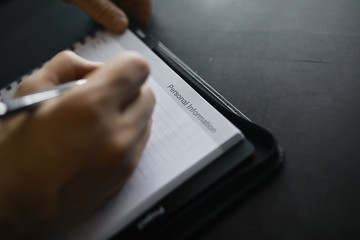 Filling out a form with personal information. Documents in a folder on the table to fill. Handwritten information about the applicant.