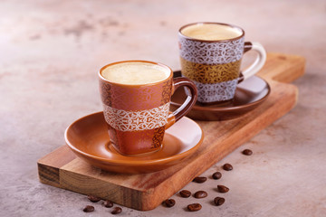 Two cups of espresso coffee on a wooden cutting board
