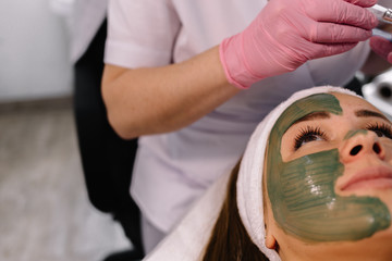 Obraz na płótnie Canvas Young woman in a spa with algae facial mask. Woman in spa salon