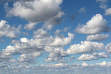 White fluffy clouds on a background of blue sky in summer. The concept of weather and climate.