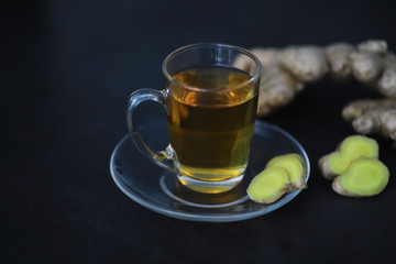 Ginger root whole and sliced. Ginger tea with lemon on the dark background. Fresh ginger root on stone background. Vitamins. Free space for your text.