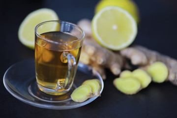 Ginger root whole and sliced. Ginger tea with lemon on the dark background. Fresh ginger root on stone background. Vitamins. Free space for your text.