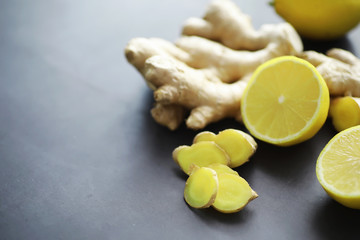 Ginger root whole and sliced. Ginger tea with lemon on the dark background. Fresh ginger root on stone background. Vitamins. Free space for your text.