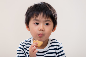 Kid boy eat cookie on white background