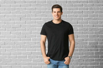 Man in stylish t-shirt on brick background - obrazy, fototapety, plakaty