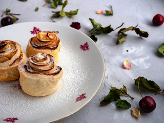 flower-shaped puff pastry. 
puff pastry with apples. flower cake on a plate. gray background with dried flowers