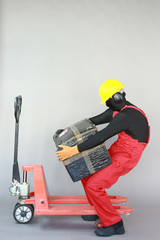  Anonymous worker dealing with heavy package at manual pallet truck.Incorrect body...