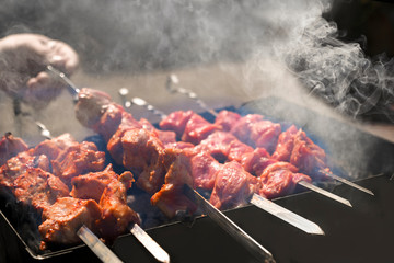 Man cooking marinated shashlik, lamb meat grilling on metal skewer. White smoke. Sale. Close up. Defocused